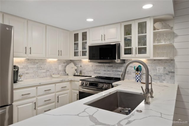 kitchen with light stone counters, white cabinetry, stainless steel appliances, and tasteful backsplash