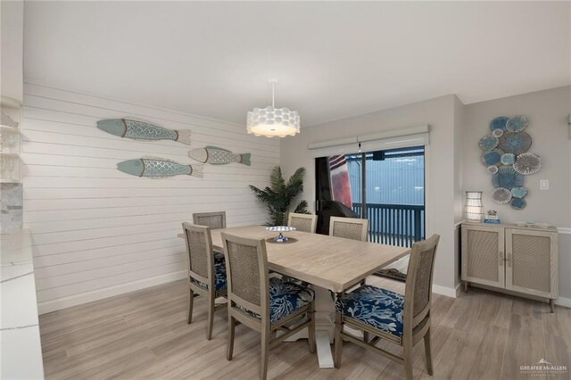 dining room featuring wooden walls and light hardwood / wood-style flooring