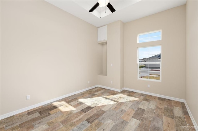 empty room featuring baseboards, a ceiling fan, and light wood-style floors