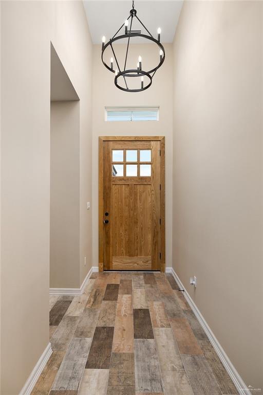 entryway with an inviting chandelier, baseboards, and wood finished floors