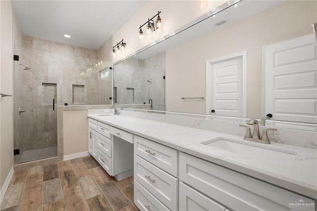 bathroom featuring double vanity, wood finish floors, a sink, and a shower stall