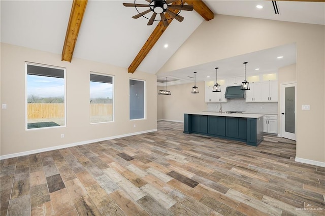 kitchen featuring ventilation hood, light countertops, light wood-style floors, white cabinetry, and backsplash