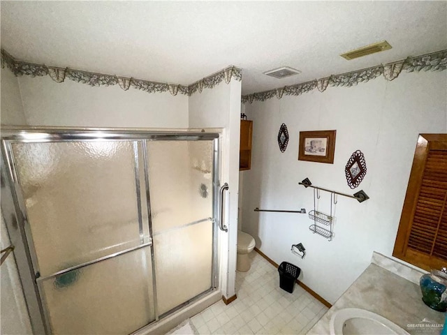 bathroom featuring a shower with door, a textured ceiling, and toilet