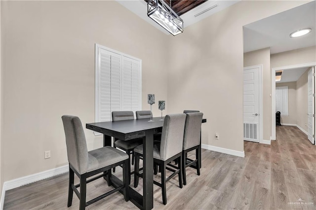 dining area with light wood-type flooring, visible vents, and baseboards