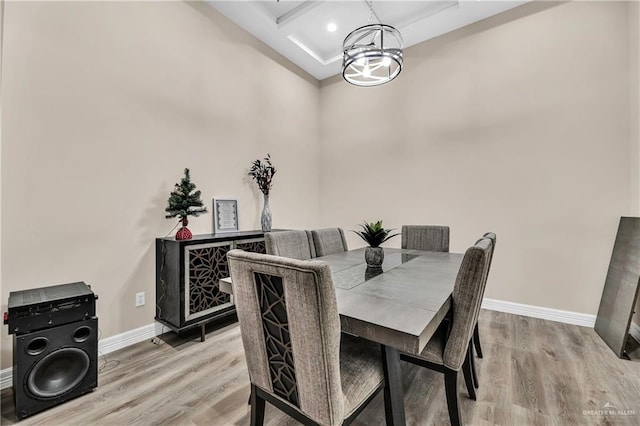 dining area featuring light wood finished floors, baseboards, coffered ceiling, and beamed ceiling