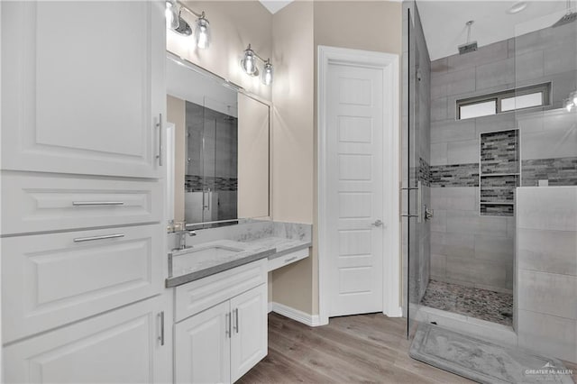 bathroom with a shower stall, baseboards, wood finished floors, and vanity