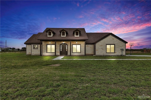 french provincial home with stone siding and a lawn