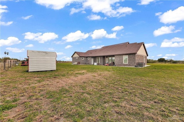 back of property featuring brick siding, a lawn, and fence