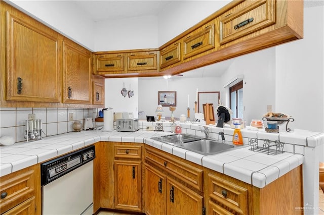 kitchen with tile counters, white dishwasher, kitchen peninsula, and sink