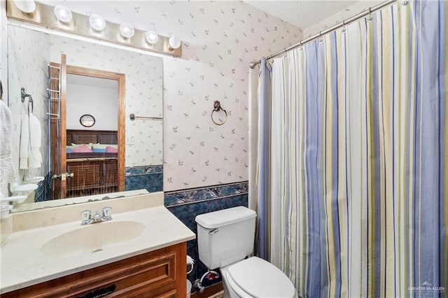 bathroom featuring vanity, a textured ceiling, toilet, and walk in shower