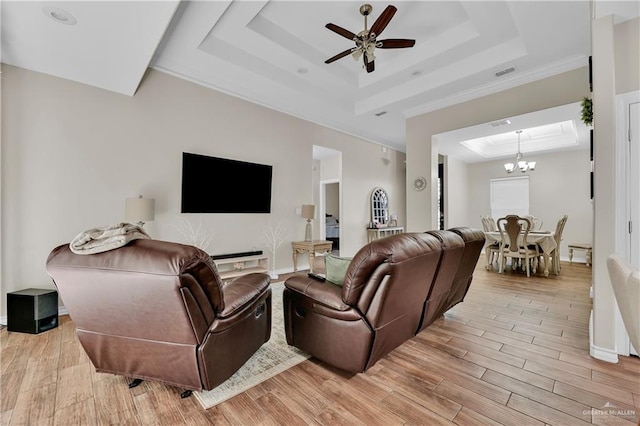 living area featuring ceiling fan with notable chandelier, a tray ceiling, light wood-style floors, and baseboards