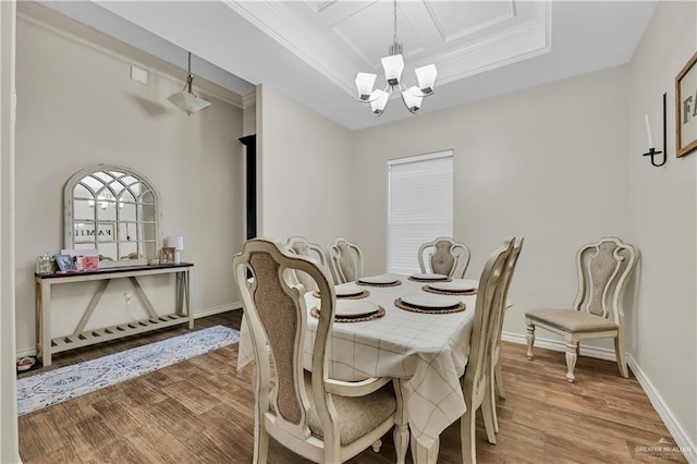 dining room featuring a chandelier, crown molding, a tray ceiling, and wood finished floors