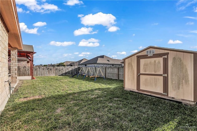 view of yard with an outbuilding, a storage unit, a playground, and a fenced backyard