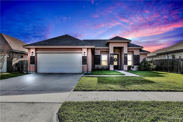 view of front facade with fence, driveway, a yard, stucco siding, and a garage