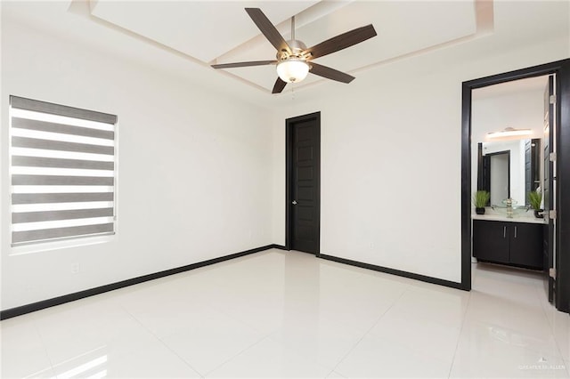 unfurnished bedroom featuring light tile patterned floors, a tray ceiling, and ensuite bath