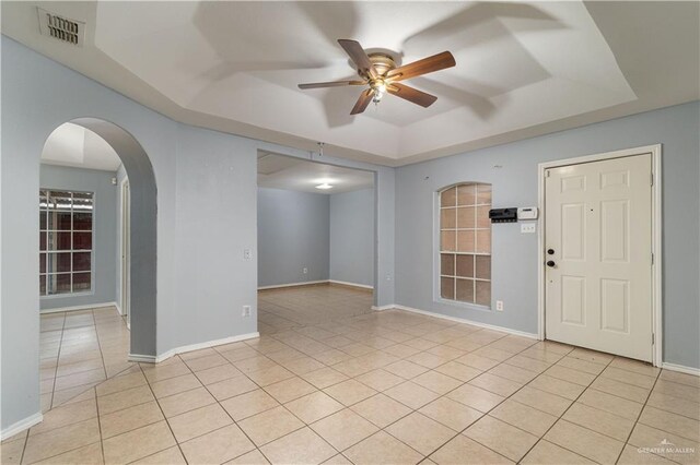 unfurnished room with light tile patterned floors, ceiling fan, and a tray ceiling