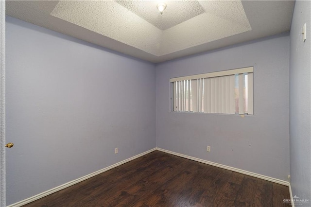 unfurnished room featuring a textured ceiling, hardwood / wood-style flooring, and a tray ceiling