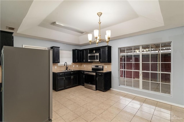 kitchen featuring light tile patterned floors, stainless steel appliances, a chandelier, and a tray ceiling