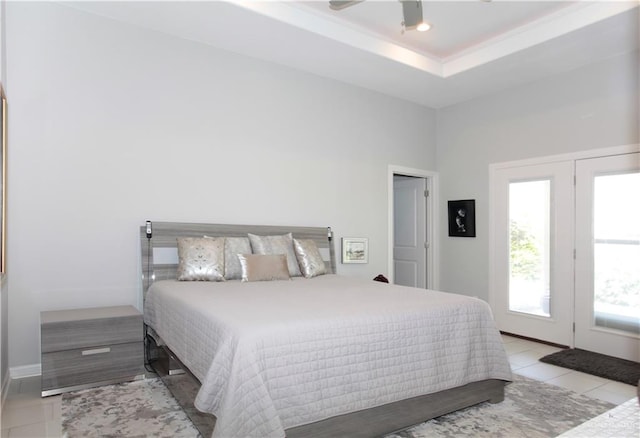 tiled bedroom with ceiling fan and a tray ceiling