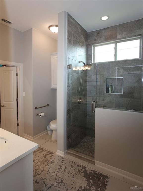 bathroom with tile patterned floors, vanity, toilet, and a shower with shower door