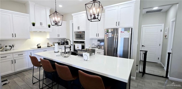 kitchen with appliances with stainless steel finishes, visible vents, under cabinet range hood, and white cabinetry