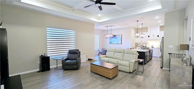 living area with light wood-style floors, a wealth of natural light, coffered ceiling, and crown molding