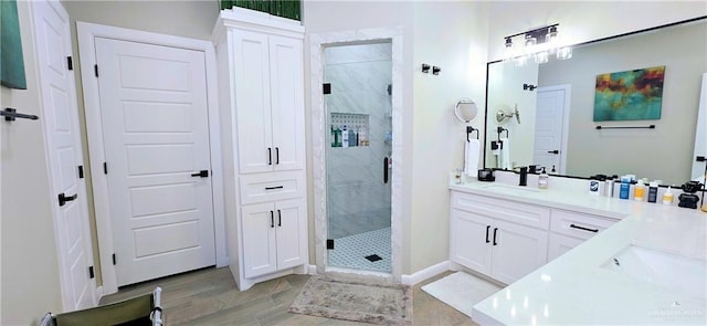 bathroom with wood finished floors, a marble finish shower, and vanity