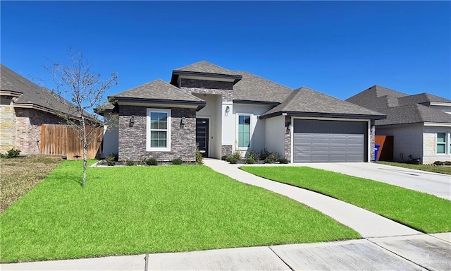 prairie-style house featuring a garage, fence, driveway, stone siding, and a front yard