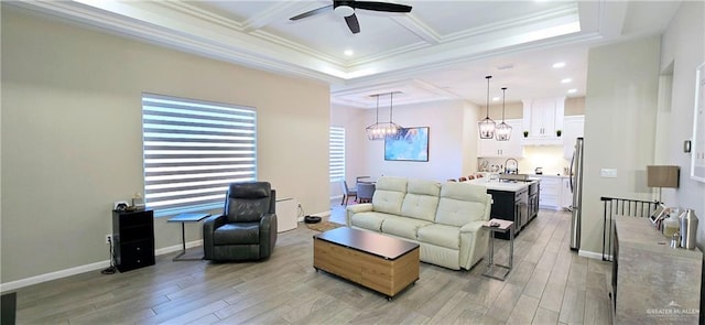 living area with crown molding, light wood-type flooring, coffered ceiling, baseboards, and ceiling fan with notable chandelier