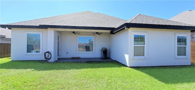 back of property featuring stucco siding, ceiling fan, roof with shingles, and a yard