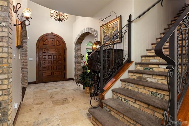 1509 Duke Ave, Mcallen, TX 78504 - foyer entrance with arched walkways, stairs, a chandelier, and stone finish flooring