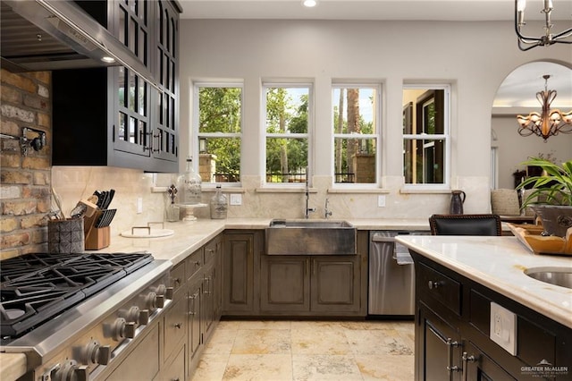 1509 Duke Ave, Mcallen, TX 78504 - kitchen featuring stainless steel appliances, a chandelier, wall chimney exhaust hood, tasteful backsplash, and arched walkways