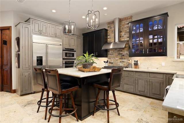 1509 Duke Ave, Mcallen, TX 78504 - kitchen featuring wall chimney exhaust hood, stainless steel appliances, decorative backsplash, a chandelier, and a center island