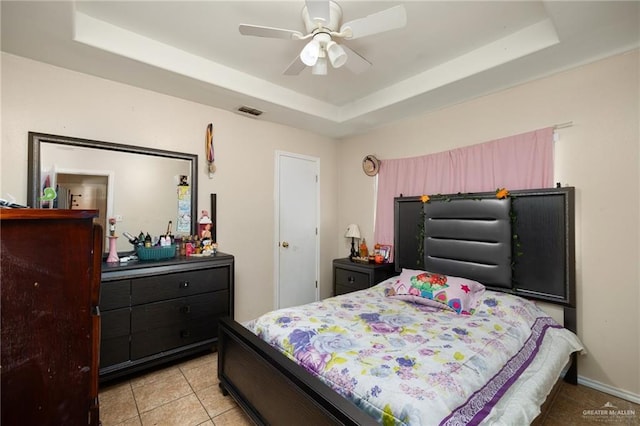 bedroom with visible vents, ceiling fan, baseboards, a tray ceiling, and light tile patterned floors