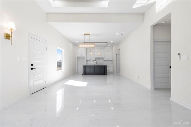 unfurnished living room with recessed lighting, marble finish floor, and baseboards