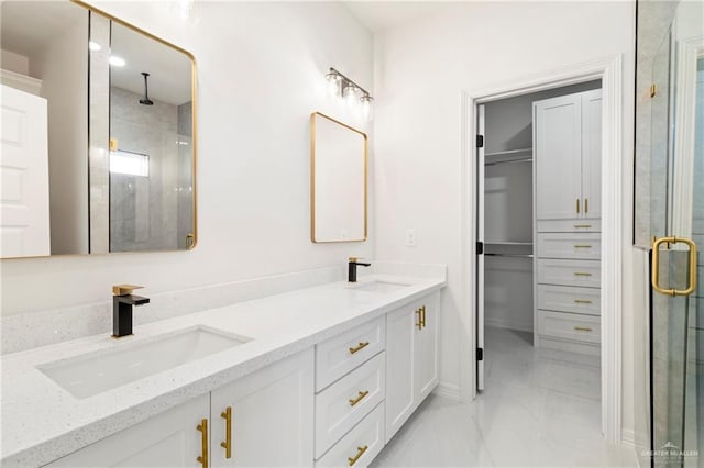 bathroom featuring marble finish floor, a spacious closet, a sink, and a shower stall