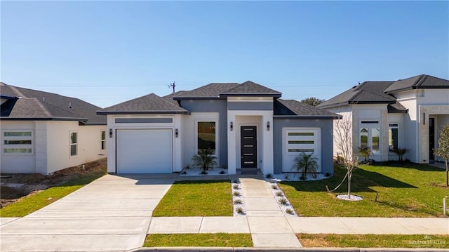 prairie-style home with roof with shingles, stucco siding, concrete driveway, an attached garage, and a front lawn