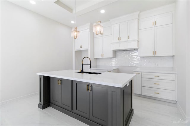 kitchen featuring light countertops, white cabinetry, a center island with sink, and hanging light fixtures