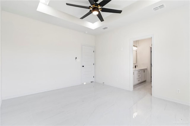 unfurnished bedroom featuring a raised ceiling, visible vents, baseboards, and ensuite bathroom