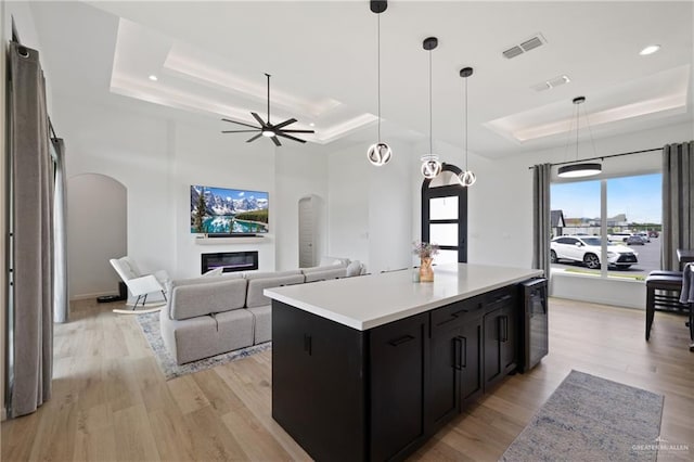 5112 W Burberry St, Edinburg, TX 78541 - kitchen featuring a raised ceiling, arched walkways, dark cabinetry, beverage cooler, and recessed lighting