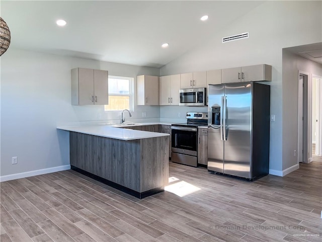 kitchen featuring stainless steel appliances, sink, kitchen peninsula, and high vaulted ceiling