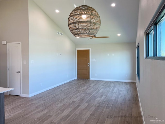 empty room featuring hardwood / wood-style flooring, ceiling fan, and a towering ceiling