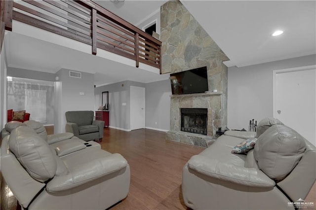 living room with crown molding, wood-type flooring, and a fireplace