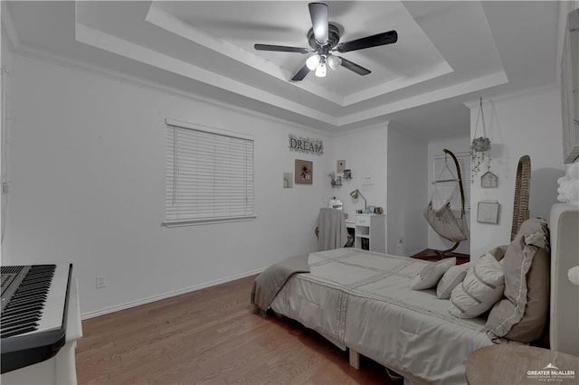 bedroom featuring light hardwood / wood-style flooring, a raised ceiling, ceiling fan, and crown molding