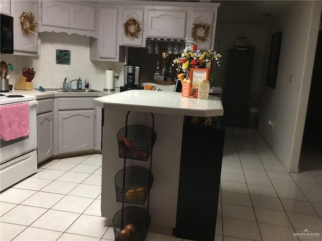 kitchen with backsplash, white range with electric cooktop, sink, light tile patterned floors, and white cabinetry