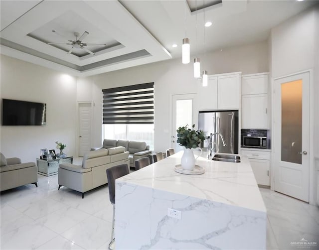 kitchen with hanging light fixtures, white cabinets, appliances with stainless steel finishes, and sink