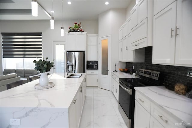 kitchen featuring an island with sink, stainless steel appliances, pendant lighting, white cabinets, and sink