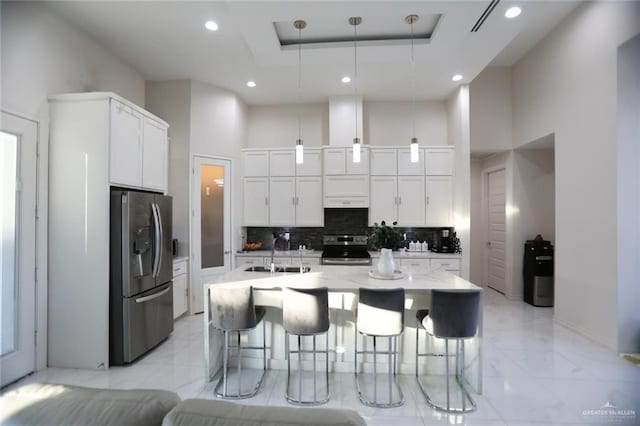 kitchen featuring white cabinetry, appliances with stainless steel finishes, a high ceiling, hanging light fixtures, and sink