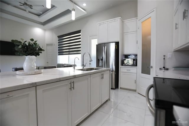 kitchen with stainless steel fridge, electric range, white cabinets, light stone counters, and sink