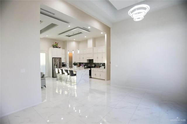 kitchen featuring white cabinetry, a breakfast bar area, stainless steel appliances, hanging light fixtures, and a kitchen island